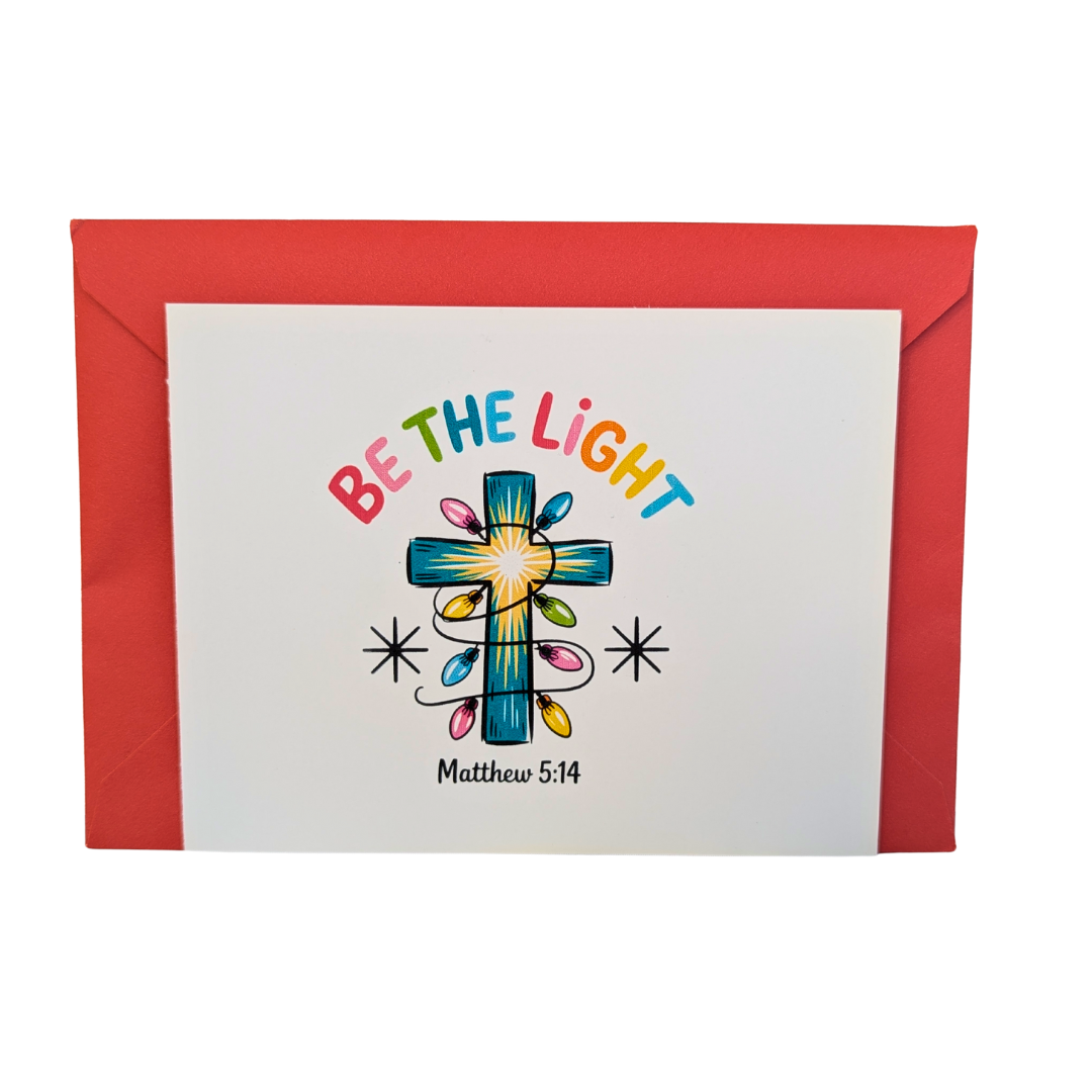 Greeting card with a cross and 'Be the Light' text on a white background with a red envelope.