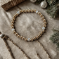 Gold and silver beaded bracelet on a textured surface with decorative elements